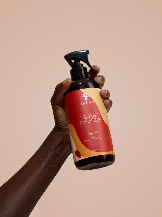ماء زيت الخروع الأسود الجامايكي As I Am Black Castor Oil Water - لقطة بورتريه لزجاجة بخاخ مرطب ممسوكة باليد، تبرز تركيبته الخفيفة المعززة بزيت الخروع الأسود الجامايكي لإنعاش وترطيب الشعر الطبيعي.