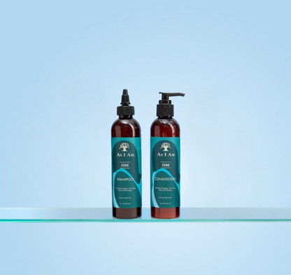 زجاجتان من شامبو وبلسم As I Am على سطح شفاف بخلفية زرقاء فاتحة