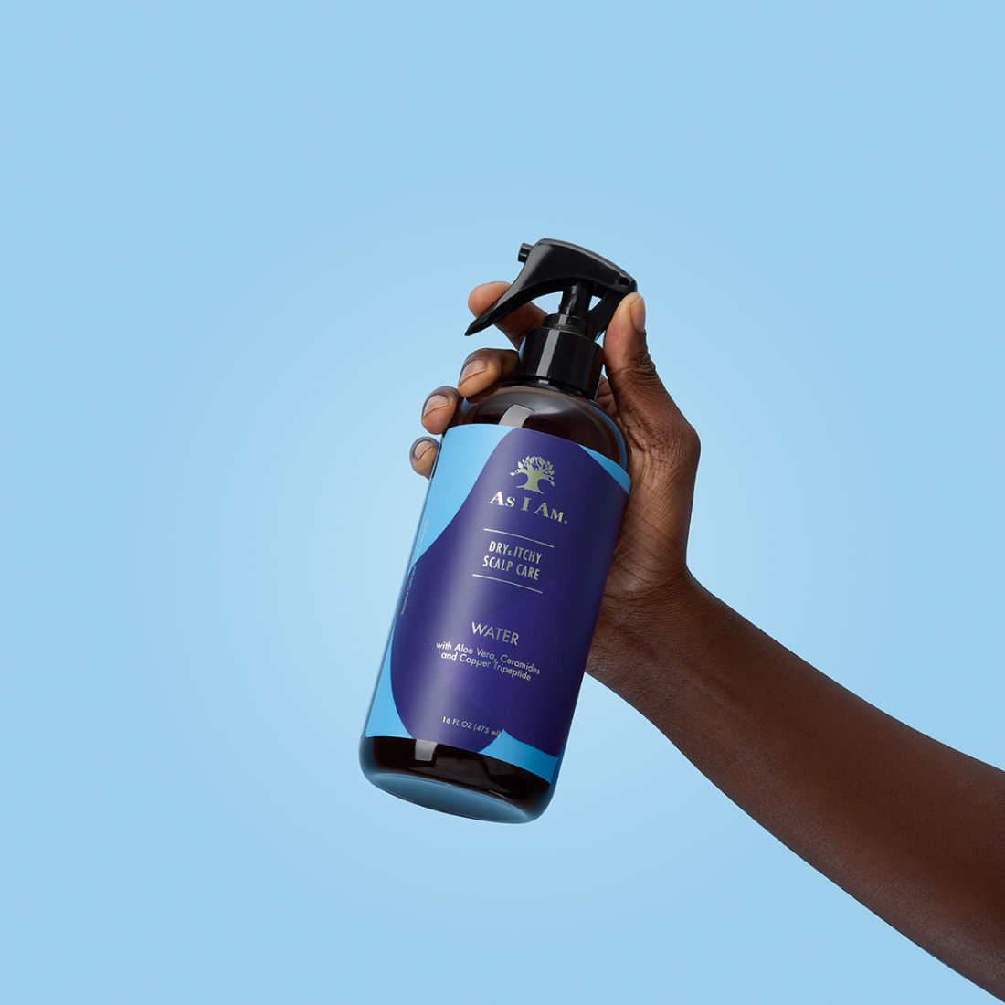 يد تحمل زجاجة من مزيل العرق AS I AM Deodorant Spray على خلفية زرقاء صافية