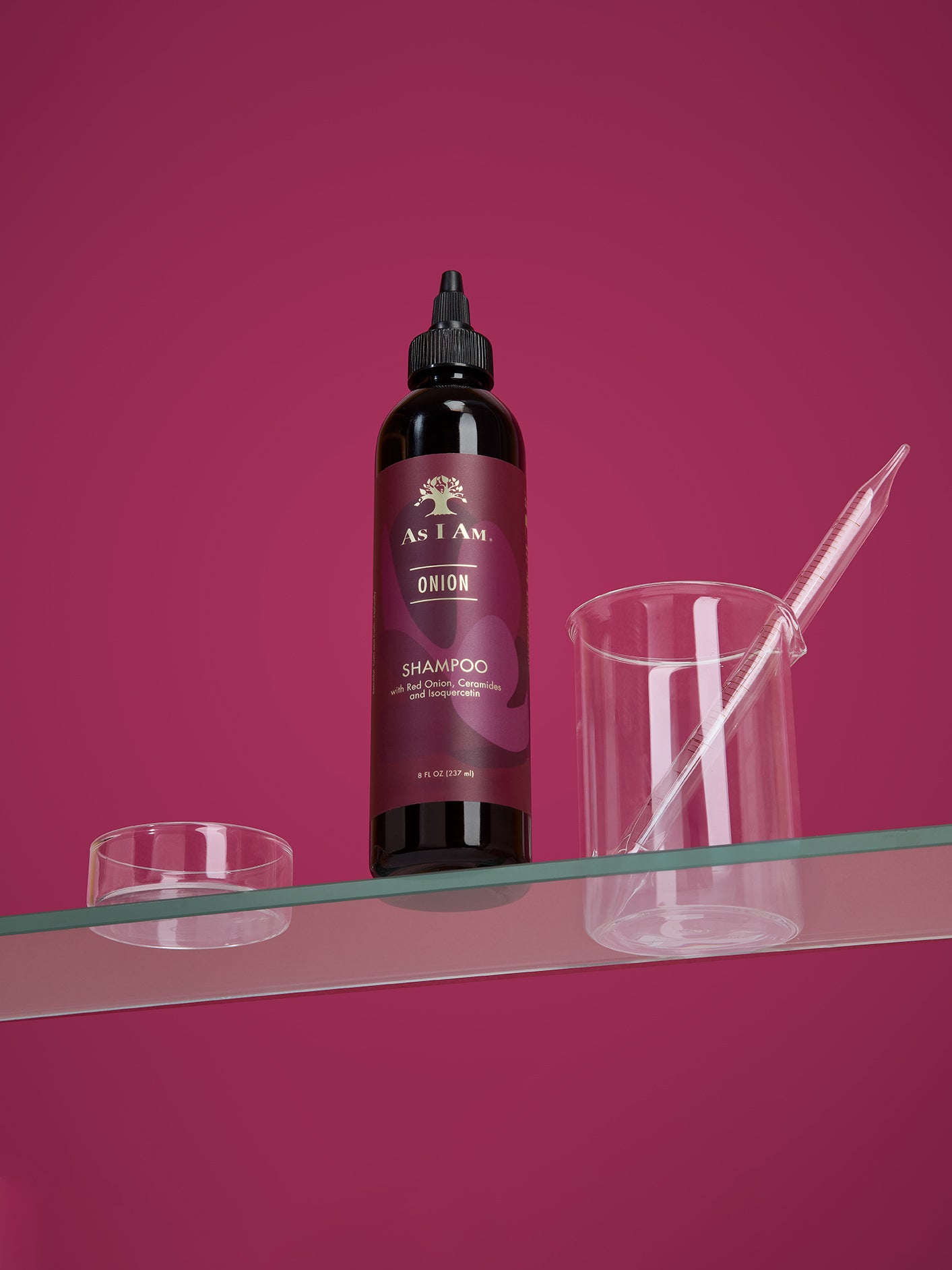 زجاجة من شامبو As I Am Onion على سطح شفاف بخلفية وردية