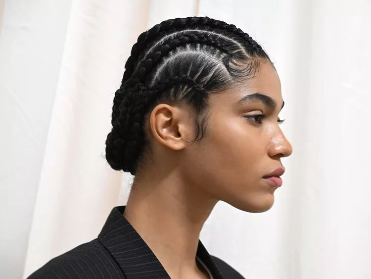 امرأة ذات شعر مضفر ترتدي ملابس سوداء على خلفية ستارة بيضاء