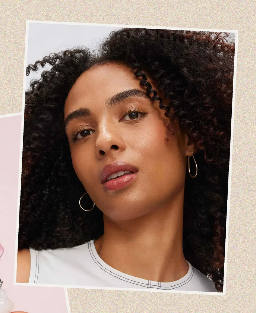 امرأة ذات شعر مجعد ترتدي أقراط حلقات على خلفية بيج